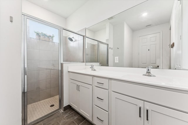 bathroom featuring a shower with door and double vanity