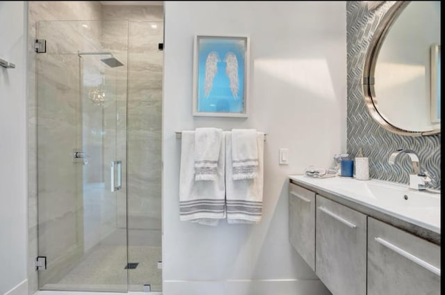 bathroom with vanity, decorative backsplash, and a shower with door