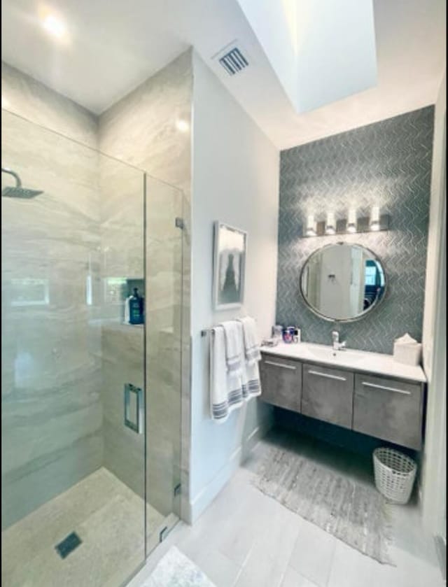 bathroom featuring a shower with door, vanity, and a skylight