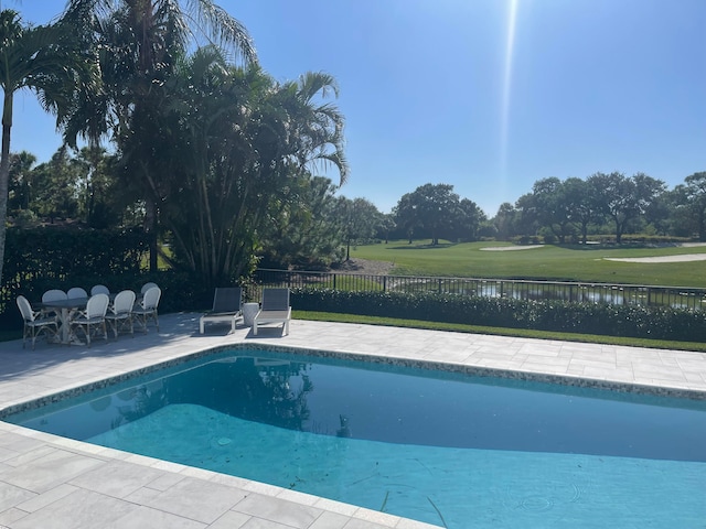 view of pool with a patio, a yard, and a water view