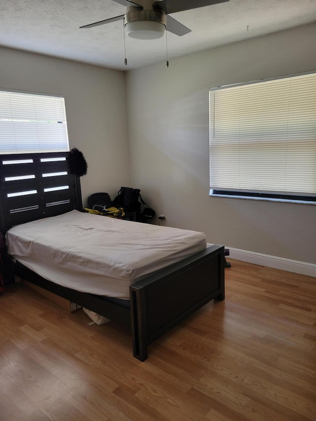 bedroom with hardwood / wood-style floors, a textured ceiling, and ceiling fan