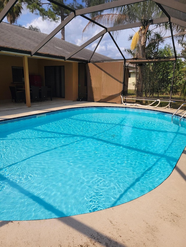 view of swimming pool featuring a patio area and a lanai