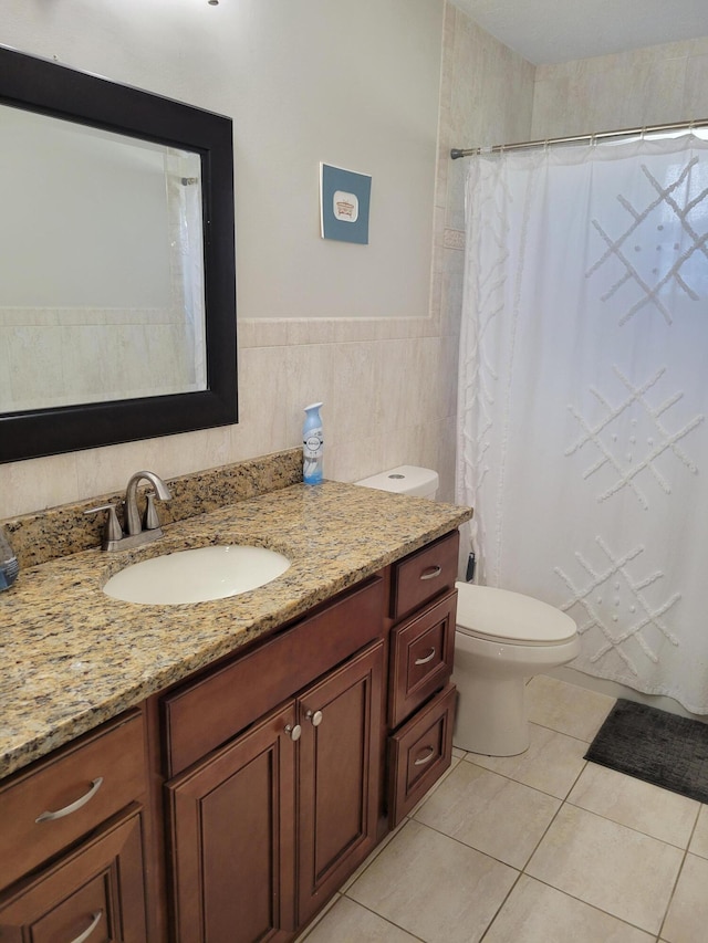 bathroom with tile walls, toilet, vanity, and tile flooring