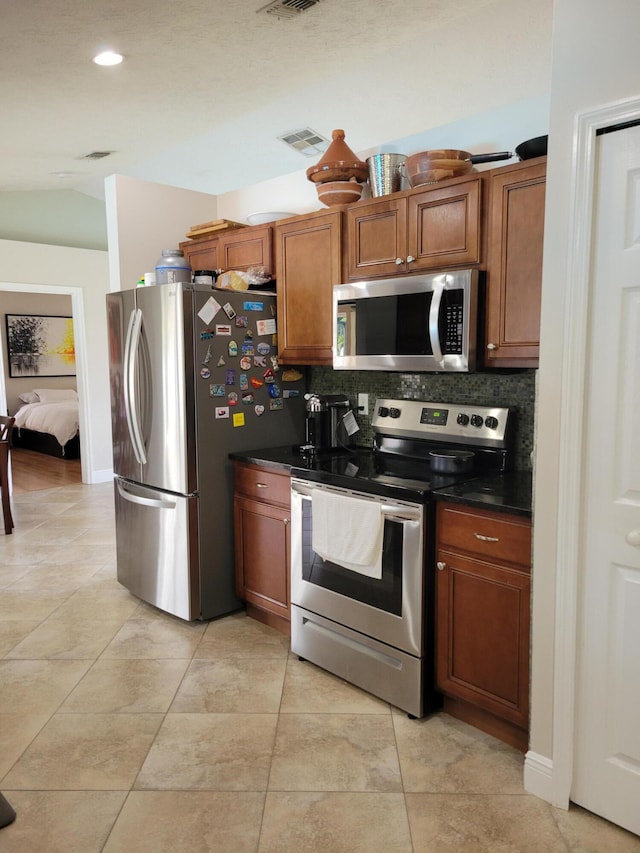 kitchen with light tile floors, appliances with stainless steel finishes, and backsplash