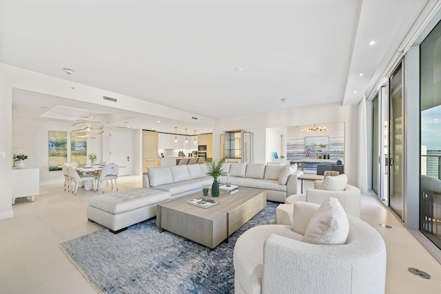 tiled living room featuring a wealth of natural light, a raised ceiling, and ceiling fan with notable chandelier