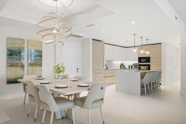 tiled dining room with a tray ceiling and a chandelier