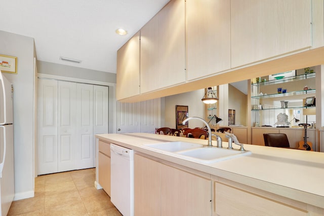 kitchen with sink, light tile floors, white dishwasher, light brown cabinetry, and pendant lighting