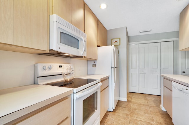 kitchen with light tile floors, light brown cabinets, and white appliances