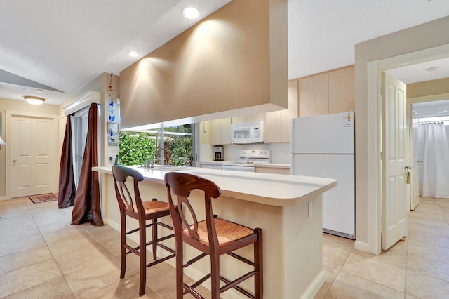 kitchen with white appliances, a kitchen bar, sink, and light tile flooring