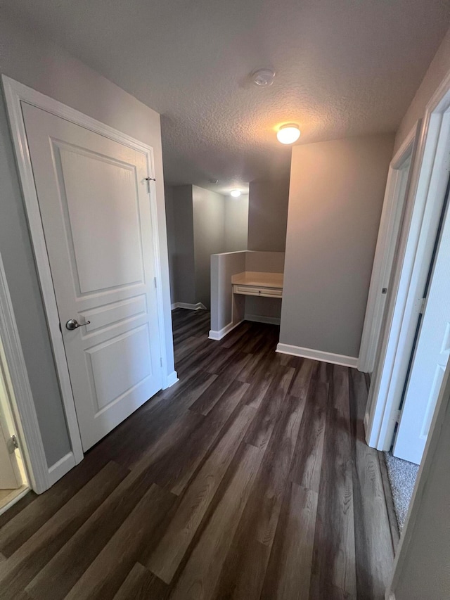 hall with a textured ceiling and dark wood-type flooring