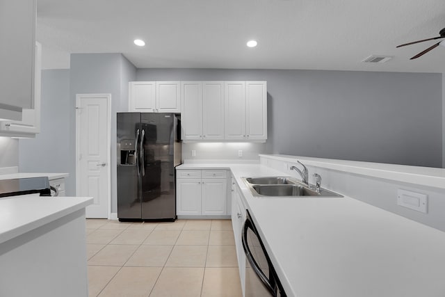 kitchen with sink, light tile patterned floors, black fridge, ceiling fan, and white cabinets