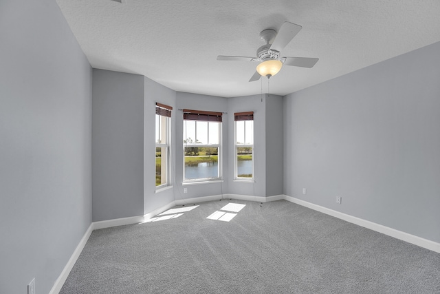 carpeted spare room featuring a textured ceiling, ceiling fan, and a water view