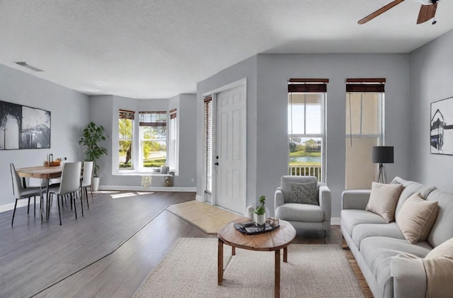 living room with a textured ceiling, ceiling fan, a healthy amount of sunlight, and hardwood / wood-style flooring