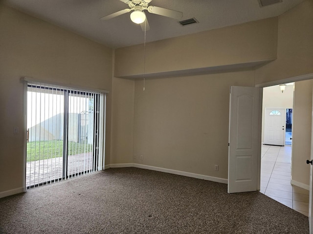 carpeted spare room with baseboards, visible vents, a ceiling fan, and tile patterned floors