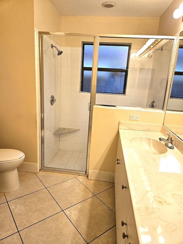 full bathroom with a stall shower, toilet, tile patterned floors, a textured ceiling, and vanity