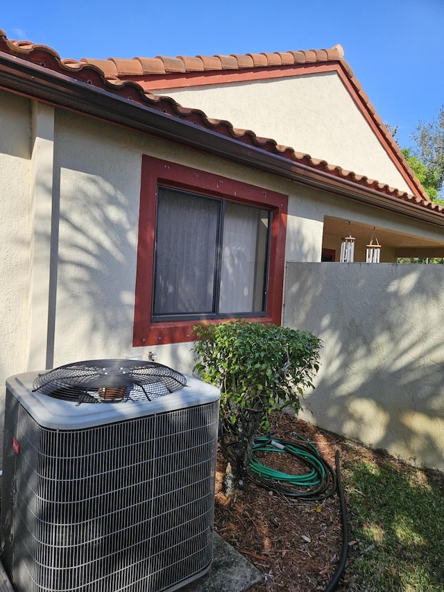 details featuring stucco siding, fence, and central AC unit