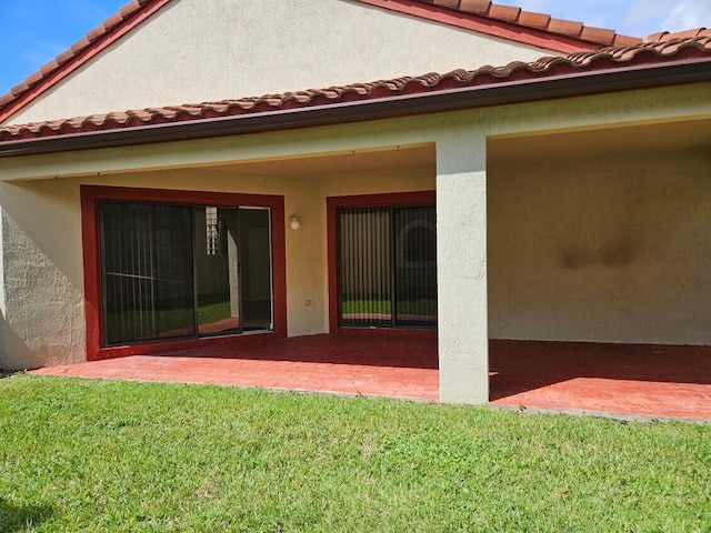 rear view of property with stucco siding, a tiled roof, and a yard