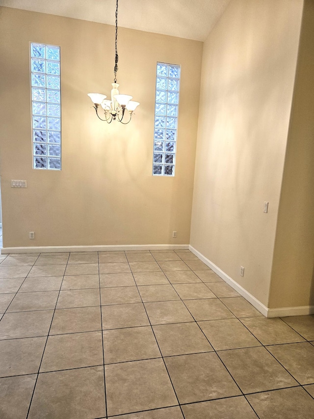 spare room with an inviting chandelier, a textured ceiling, plenty of natural light, and light tile patterned floors