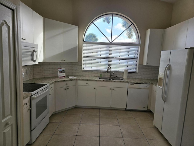 kitchen featuring light tile patterned floors, white appliances, a sink, white cabinets, and tasteful backsplash