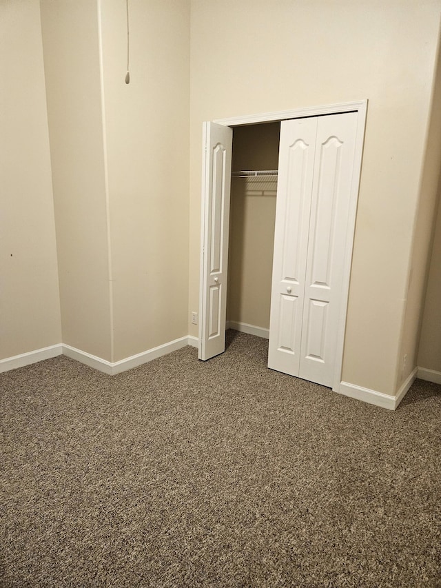 unfurnished bedroom featuring a closet, baseboards, and carpet flooring