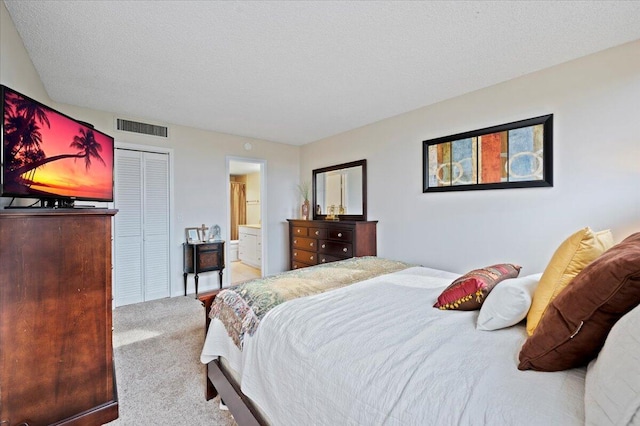 carpeted bedroom featuring a closet, a textured ceiling, and ensuite bath