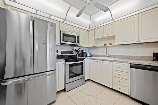 kitchen featuring stainless steel appliances, sink, ceiling fan, light tile patterned floors, and decorative backsplash