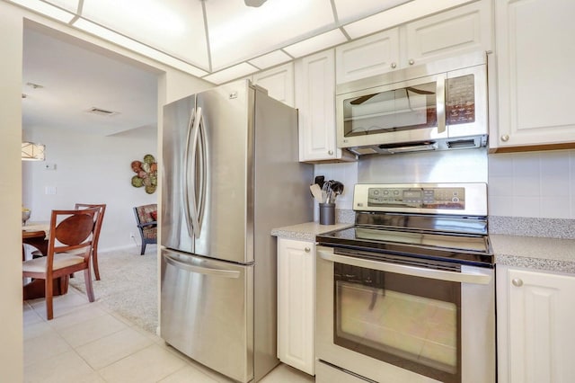 kitchen with tasteful backsplash, white cabinetry, appliances with stainless steel finishes, and light tile patterned flooring