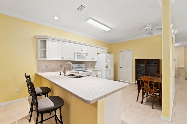 kitchen with kitchen peninsula, a kitchen breakfast bar, crown molding, sink, and white appliances