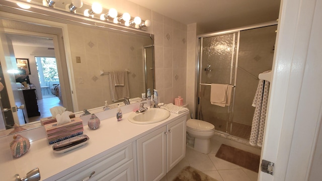 bathroom with toilet, large vanity, tile floors, and walk in shower