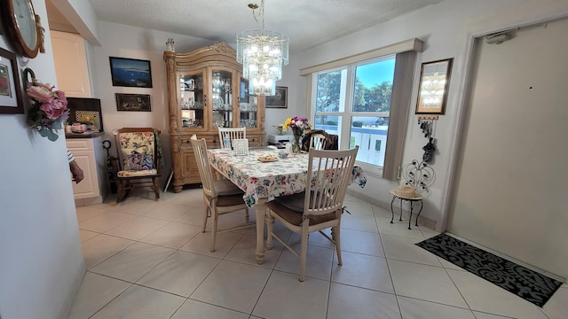 tiled dining room with a textured ceiling and a chandelier