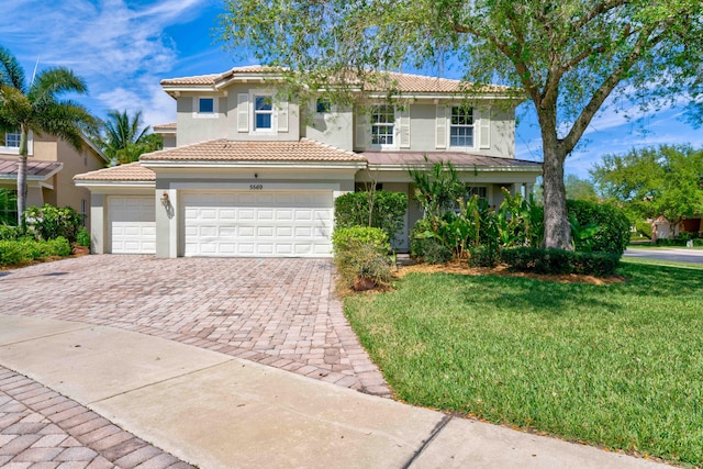 mediterranean / spanish home featuring a front lawn and a garage