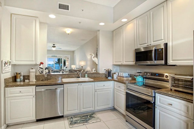 kitchen with white cabinets, light tile patterned floors, stainless steel appliances, ceiling fan, and sink