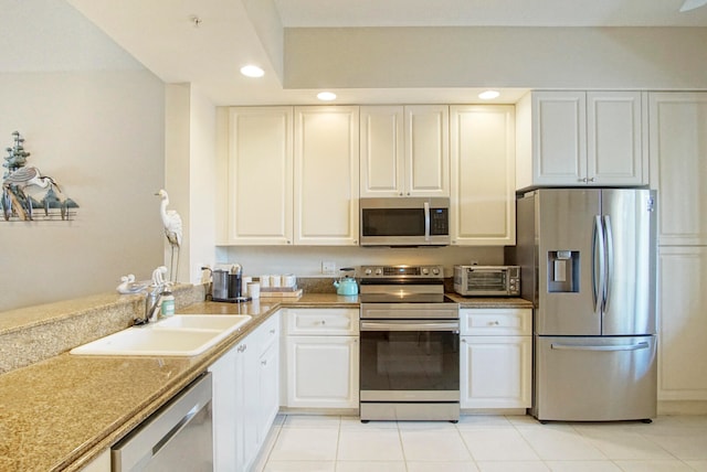 kitchen with light tile patterned flooring, stainless steel appliances, sink, and white cabinetry