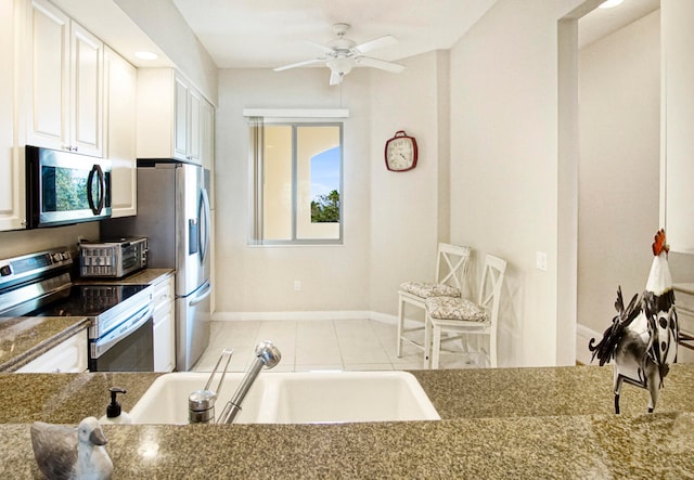 kitchen with white cabinetry, light tile patterned floors, stainless steel appliances, ceiling fan, and sink