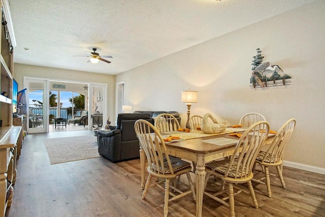 dining space with ceiling fan, hardwood / wood-style flooring, and a textured ceiling