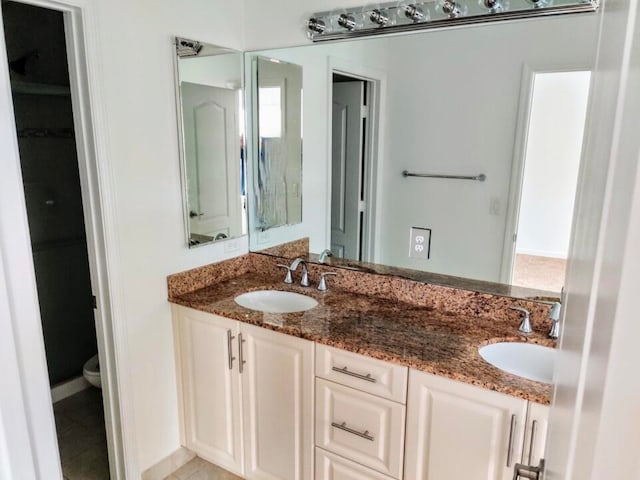 bathroom featuring toilet, double sink, large vanity, and tile flooring