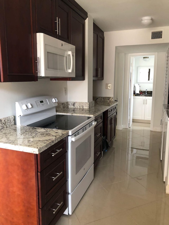 kitchen featuring white appliances, light stone countertops, sink, and light tile floors