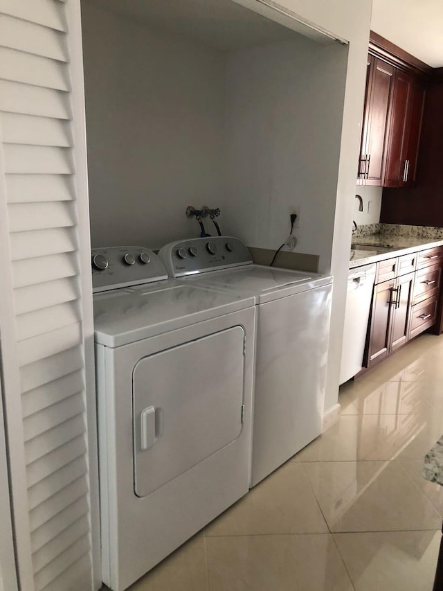 clothes washing area featuring light tile floors, sink, and independent washer and dryer