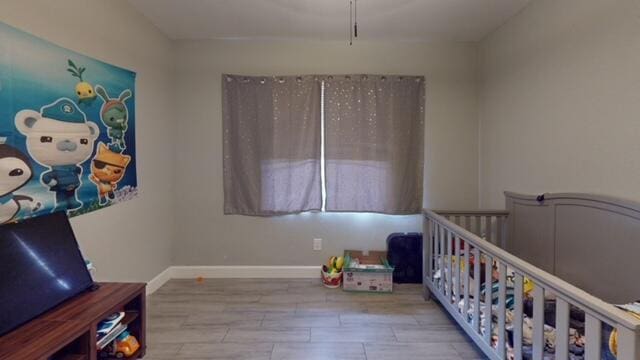 bedroom with a crib and light hardwood / wood-style flooring