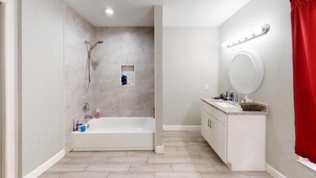 bathroom featuring tiled shower / bath combo and vanity with extensive cabinet space