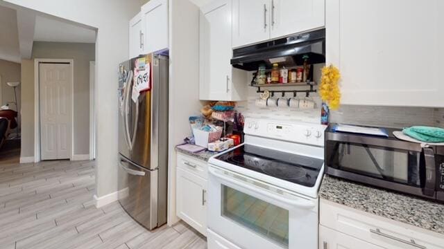 kitchen with white cabinets, light stone countertops, light hardwood / wood-style floors, and appliances with stainless steel finishes