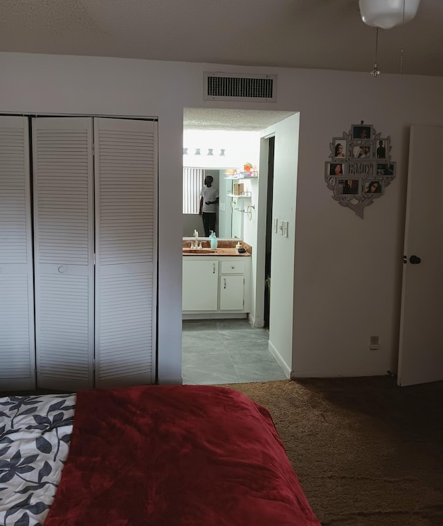 bedroom featuring a closet, sink, ensuite bathroom, and light tile floors