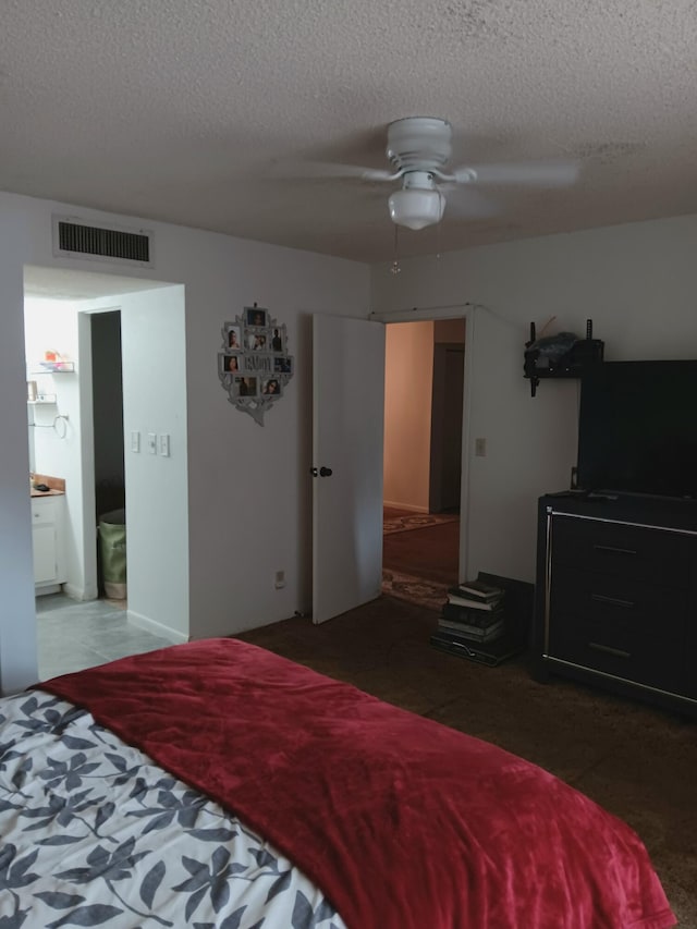 bedroom with ensuite bath, a textured ceiling, and ceiling fan