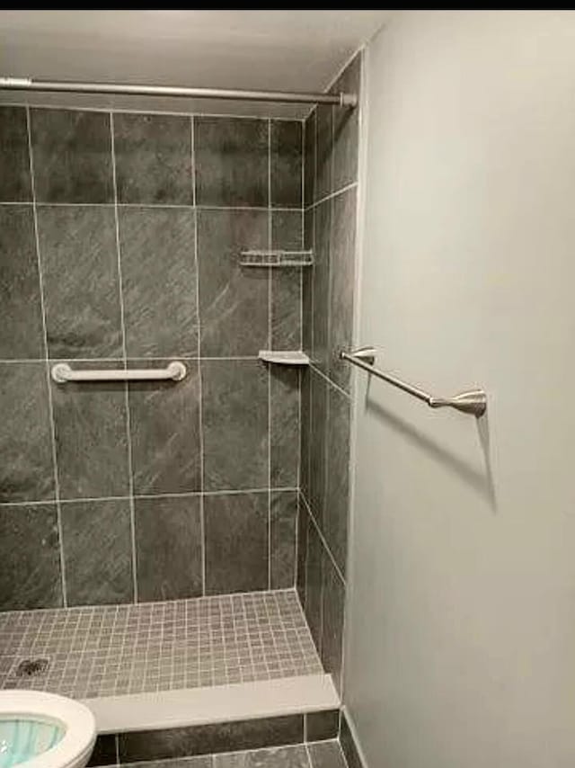 bathroom featuring toilet and a tile shower