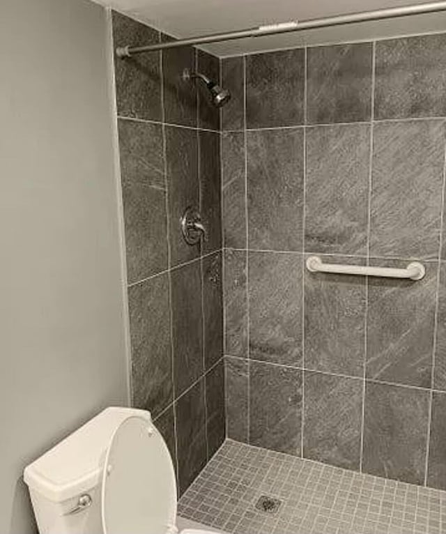 bathroom with tiled shower and toilet