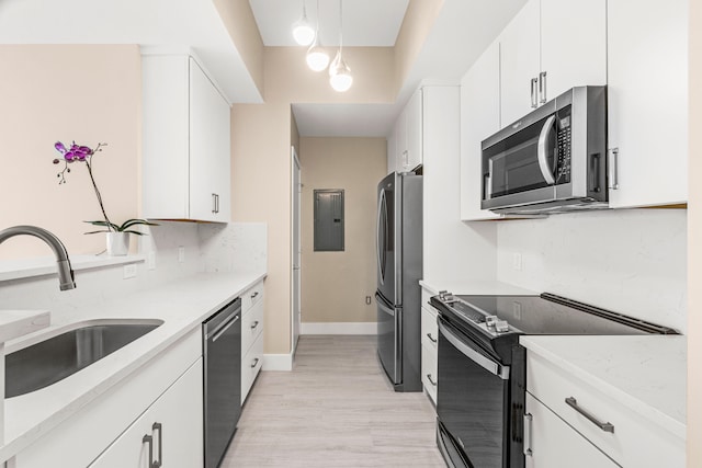 kitchen with decorative light fixtures, appliances with stainless steel finishes, white cabinetry, and light hardwood / wood-style floors