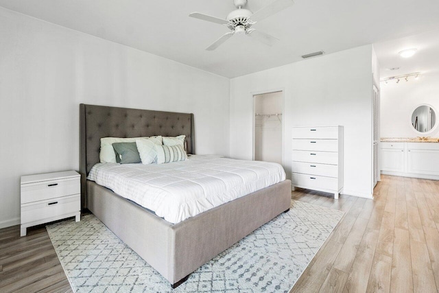 bedroom featuring ensuite bath, light hardwood / wood-style floors, a walk in closet, ceiling fan, and a closet