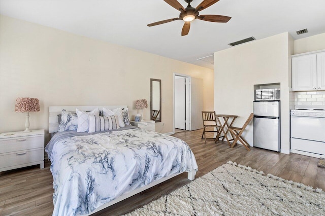 bedroom featuring stainless steel refrigerator, ceiling fan, and dark wood-type flooring