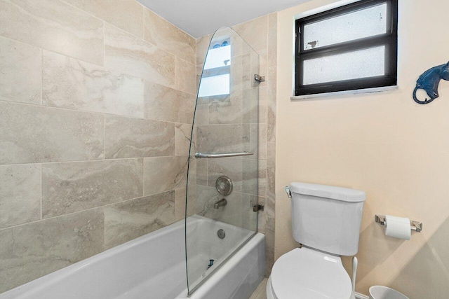 bathroom with enclosed tub / shower combo, toilet, and a wealth of natural light