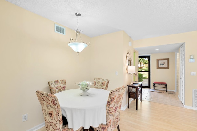 dining area featuring light tile floors and a textured ceiling